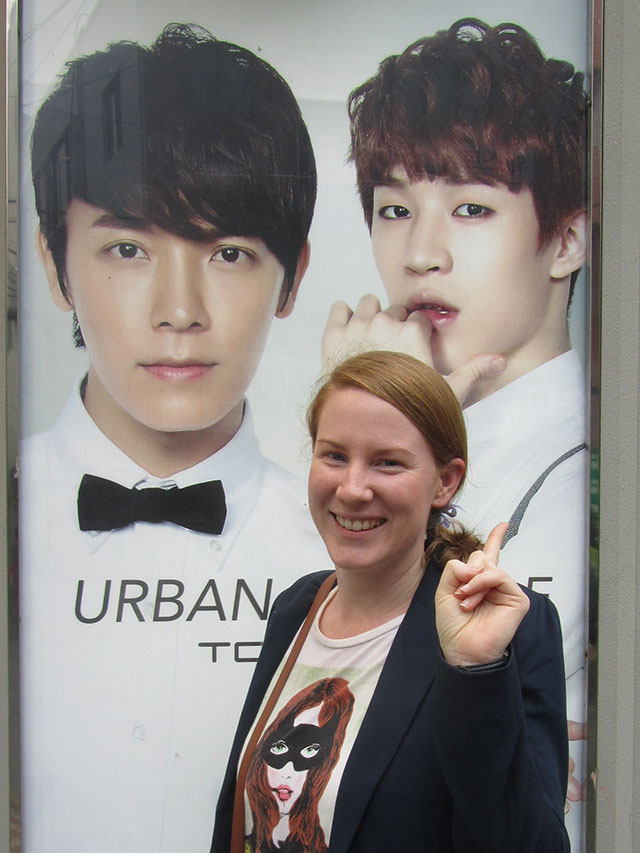 Angela posing with K-pop poster