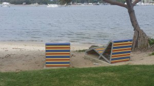 Two beach chairs under a pandanus palm overlook the water.