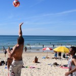 Students playing volleyball on the beach.