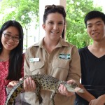 Two students and a staff member from Currumbin Wildlife Sanctuary pose with baby crocodile.