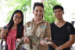Two students and a staff member from Currumbin Wildlife Sanctuary pose with baby crocodile.