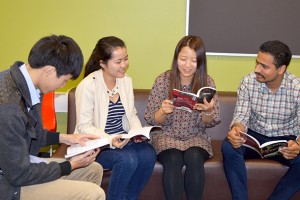 Four students are sitting on a couch reviewing the book club book.