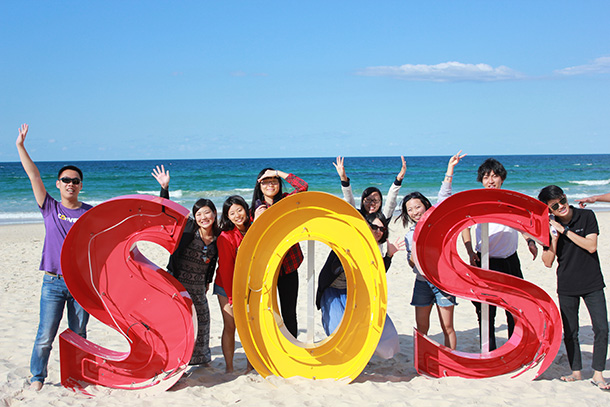 GELI students stand behind giant letters that read "S.O.S."