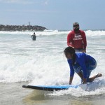 Tharshika practises as her learn to surf instructor watches over her.