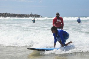 Tharshika practises as her learn to surf instructor watches over her.