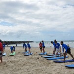 International Student Ambassadors practise surfing on the sand.