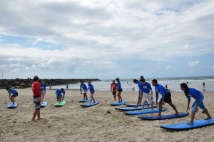 International Student Ambassadors practise surfing on the sand.