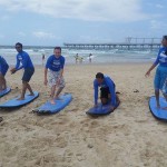 International Student Ambassadors practise surfing on the sand.