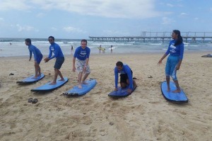International Student Ambassadors practise surfing on the sand.