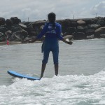 Tharshika standing upright and surfing.