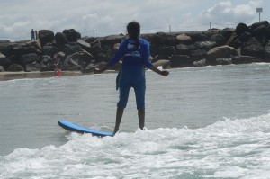 Tharshika standing upright and surfing.