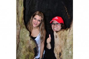 2 students inside a burnt out tree in the forest.