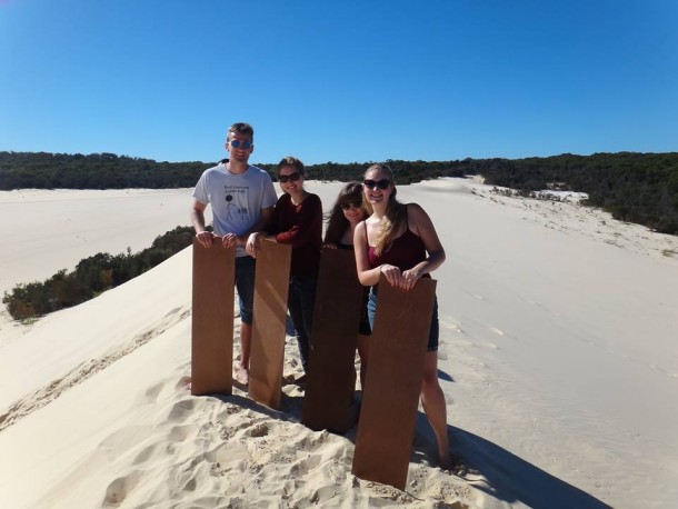 Jordan and friends stand on top of sand dunes ready to toboggan down them.