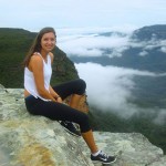 Melissa sitting on rocks above the clouds in the Blue Mountains NSW