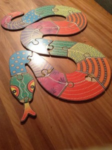 Snake jigsaw puzzle painted with Aboriginal Australian art.