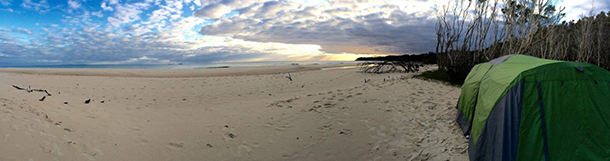 Panorama view of the beach with blue and white tent in the foreground