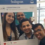 Four conference delegates pose with giant Instagram frame.