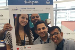 Four conference delegates pose with giant Instagram frame.